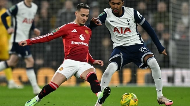 Gelandang Manchester United asal Brasil, Antony (kiri) berebut dengan bek Tottenham Hotspur asal Inggris, Djed Spence selama pertandingan perempat final Piala Liga Inggris di Stadion Tottenham Hotspur di London, pada 19 Desember 2024. Tottenham memenangkan pertandingan dengan skor 4-3. Ben STANSALL / AFP