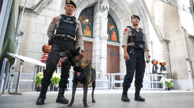 Anggota kepolisian melakukan sterilisasi di Gereja Katedral Jakarta atau Gereja Santa Maria Diangkat Ke Surga menjelang perayaan Hari Raya Natal di Jakarta, Selasa (24/12/2024). [Suara.com/Alfian Winanto]