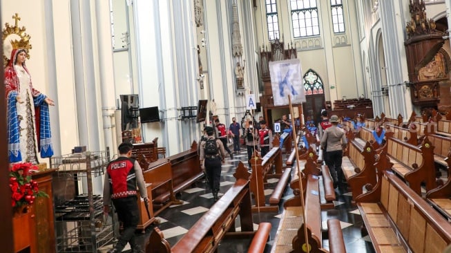 Anggota kepolisian melakukan sterilisasi di Gereja Katedral Jakarta atau Gereja Santa Maria Diangkat Ke Surga menjelang perayaan Hari Raya Natal di Jakarta, Selasa (24/12/2024). [Suara.com/Alfian Winanto]