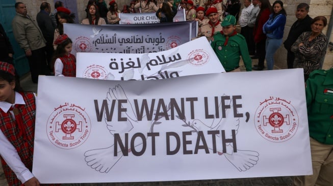 Pramuka Palestina mengambil bagian dalam prosesi Natal tahunan menuju Gereja Kelahiran di kota Betlehem di Tepi Barat Palestina yang diduduki Israel pada Selasa (24/12/2024).[HAZEM BADER / AFP]