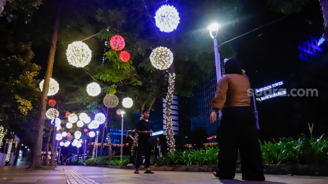 Pejalan kaki melintas di trotoar Jalan Jenderal Sudirman, Jakarta, Rabu (25/12/2024). [Suara.com/Alfian Winanto]