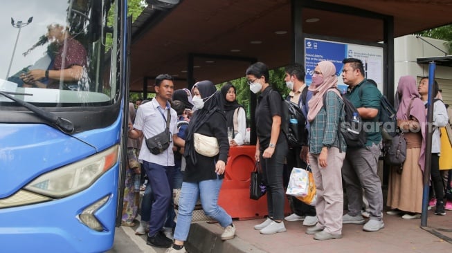 Warga antre untuk menaiki bus tingkat wisata TransJakarta di kawasan Monas, Jakarta, Kamis (26/12/2024). [Suara.com/Alfian Winanto]