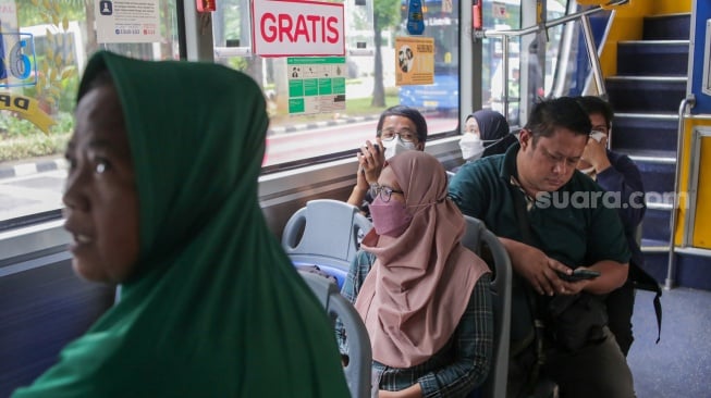 Warga menaiki bus tingkat wisata TransJakarta di kawasan Monas, Jakarta, Kamis (26/12/2024). [Suara.com/Alfian Winanto]