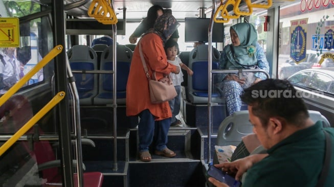 Warga menaiki bus tingkat wisata TransJakarta di kawasan Monas, Jakarta, Kamis (26/12/2024). [Suara.com/Alfian Winanto]