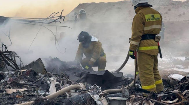 Petugas mengevakuasi puing-puing di lokasi jatuhnya pesawat penumpang Azerbaijan Airlines di dekat kota Aktau di Kazakhstan barat, Rabu (25/12/2024). [Handout / Kazakhstan's emergency situations ministry / AFP]