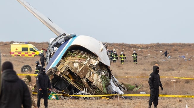 Petugas mengevakuasi puing-puing di lokasi jatuhnya pesawat penumpang Azerbaijan Airlines di dekat kota Aktau di Kazakhstan barat, Rabu (25/12/2024). [Kamilla Jumayeva / AFP]