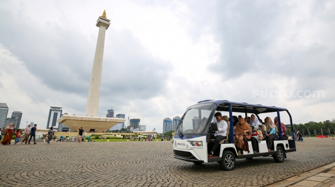 Pengunjung berwisata di kawasan Monas, Jakarta, Jumat (27/12/2024). [Suara.com/Alfian Winanto]