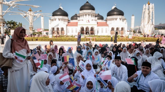 Anak-anak mengibarkan bendera nasional saat salat di Masjid Raya Baiturrahman untuk memperingati 20 tahun bencana tsunami 2004 di Banda Aceh, Indonesia, Kamis (26/12/2024). [Yasuyoshi CHIBA / AFP]