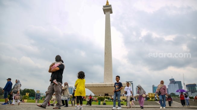 Pengunjung berwisata di kawasan Monas, Jakarta, Jumat (27/12/2024). [Suara.com/Alfian Winanto]