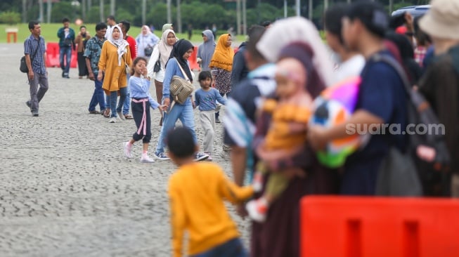 Pengunjung berwisata di kawasan Monas, Jakarta, Jumat (27/12/2024). [Suara.com/Alfian Winanto]