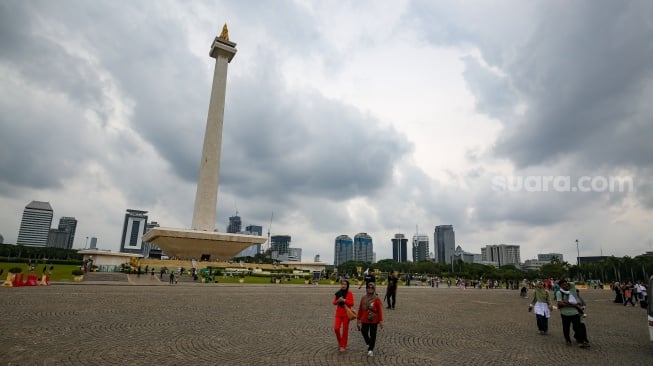 Pengunjung berwisata di kawasan Monas, Jakarta, Jumat (27/12/2024). [Suara.com/Alfian Winanto]