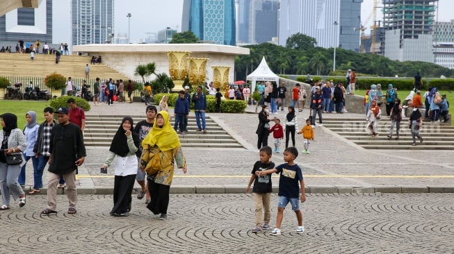 Pengunjung berwisata di kawasan Monas, Jakarta, Jumat (27/12/2024). [Suara.com/Alfian Winanto]