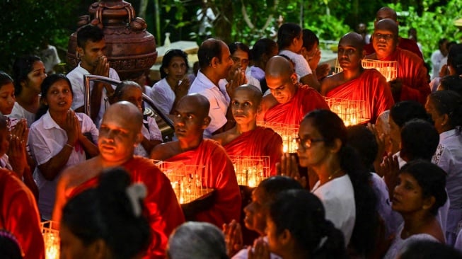 Para biksu Buddha memegang lampu minyak selama acara peringatan 20 tahun bencana tsunami 2004 di Biara Buddha Mahamevnawa di Galle, Sri Lanka, Kamis (26/12/2024). [Ishara S. KODIKARA / AFP]