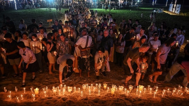 Pengunjung meletakkan lilin di pantai di Taman Peringatan Tsunami Ban Nam Khem di provinsi Phang Nga, Thailand selatan, Kamis (26/12/2024). [Lillian SUWANRUMPHA / AFP]