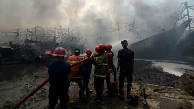 Petugas berusaha memadamkan api saat kebakaran kapal nelayan di Pelabuhan Tegal, Jawa Tengah, Jumat (27/12/2024). [ANTARA FOTO/Oky Lukmansyah/nym]