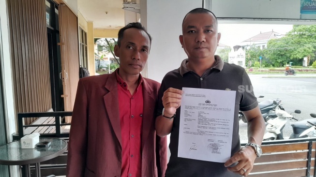 Winnar Batara bersama kliennya HS menunjukkan bukti laporan ke Polda Kaltim terkait dugaan Kejahatan Bank. [SuaraKaltim.id/Arif Fadillah]