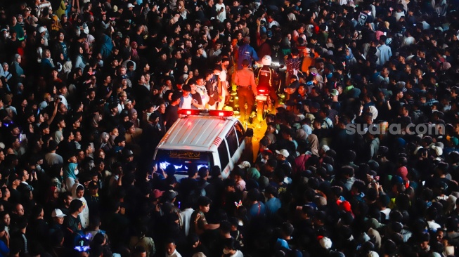 Mobil Ambulans mencoba melewati kerumuna warga saat Car Free Night menyambut malam pergantian tahun di Bundaran HI, Jakarta, Selasa (31/12/2024). [Suara.com/Alfian Winanto]