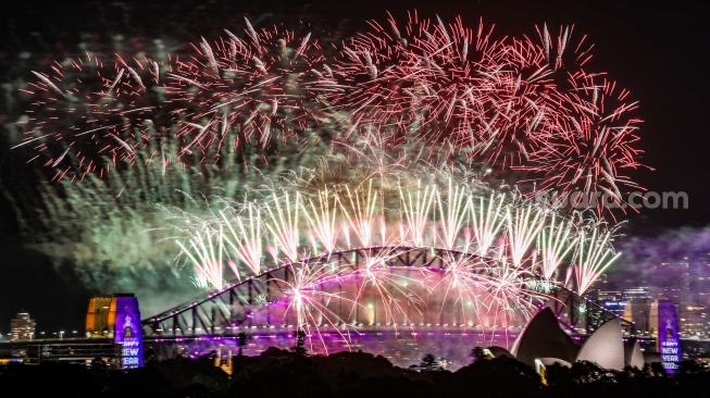 Kembang api menerangi langit tengah malam di atas Jembatan Pelabuhan Sydney dan Gedung Opera Sydney selama perayaan Tahun Baru 2025 di Sydney, Australia, Rabu (1/1/2025). [David GRAY / AFP]