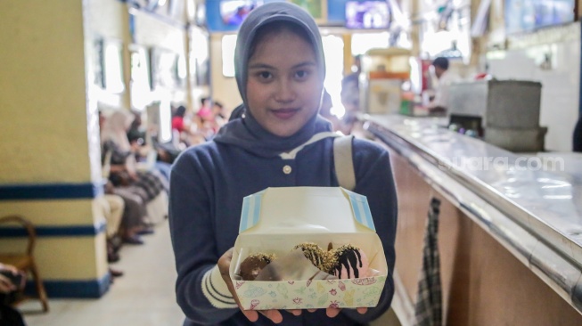 Pengunjung menunjukan es krim yang dibelinya di Ragusa Es Italia di Jakarta, Rabu (1/1/2025). [Suara.com/Alfian Winanto]