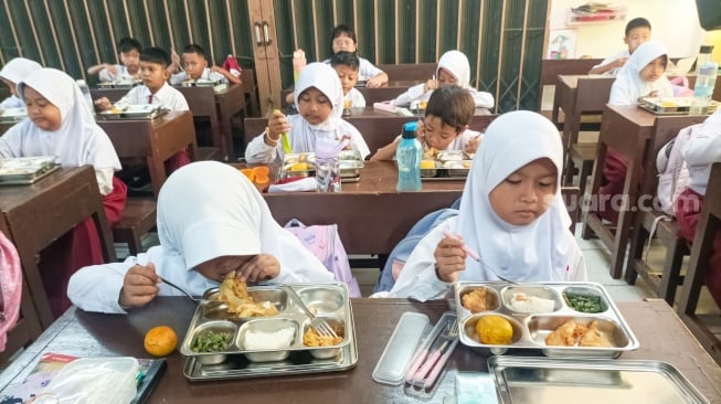 Para siswa menyantap Makanan Bergizi gratis di SDN 15 Slipi, Jakarta, Senin (6/1/2025). [Suara.com/Alfian Winanto]