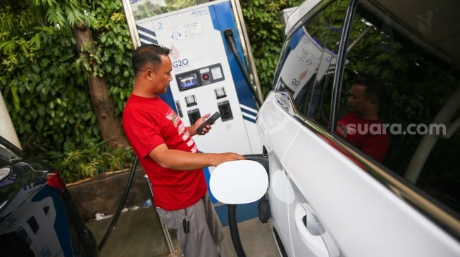 Pemilik kendaraan melakukan pengisian daya kendaraan listrik di SKPLU, Jakarta, Kamis (9/1/2025). [Suara.com/Alfian Winanto]