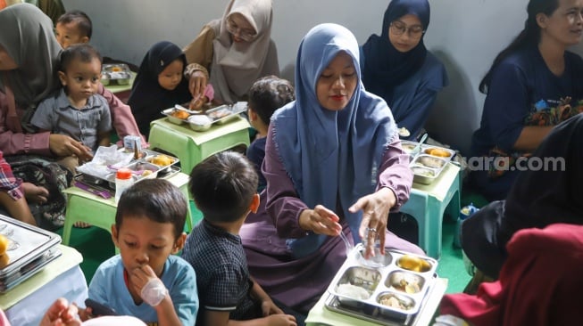 Warga menyantap hidangan Makan Bergizi Gratis (MBG) di kawasan Ciracas, Jakarta, Jumat (10/1/2025). [Suara.com/Alfian Winanto]