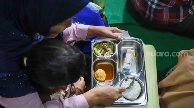 Warga menyantap hidangan Makan Bergizi Gratis (MBG) di kawasan Ciracas, Jakarta, Jumat (10/1/2025). [Suara.com/Alfian Winanto]