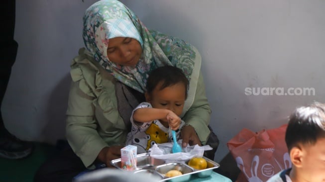 Warga menyantap hidangan Makan Bergizi Gratis (MBG) di kawasan Ciracas, Jakarta, Jumat (10/1/2025). [Suara.com/Alfian Winanto]