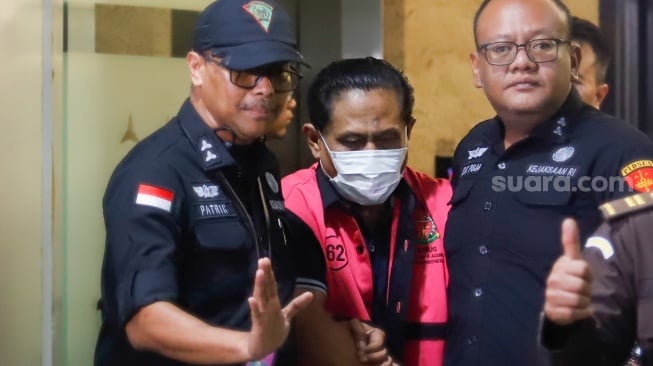 Petugas menggiring tersangka kasus dugaan suap hakim pembebas Gregorius Ronald Tannur Rudi Suparmono (tengah) keluar dari Gedung Kejaksaan Agung, Jakarta, Selasa (14/1/2025). [Suara.com/Alfian Winanto]