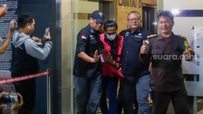 Petugas menggiring tersangka kasus dugaan suap hakim pembebas Gregorius Ronald Tannur Rudi Suparmono (tengah) keluar dari Gedung Kejaksaan Agung, Jakarta, Selasa (14/1/2025). [Suara.com/Alfian Winanto]