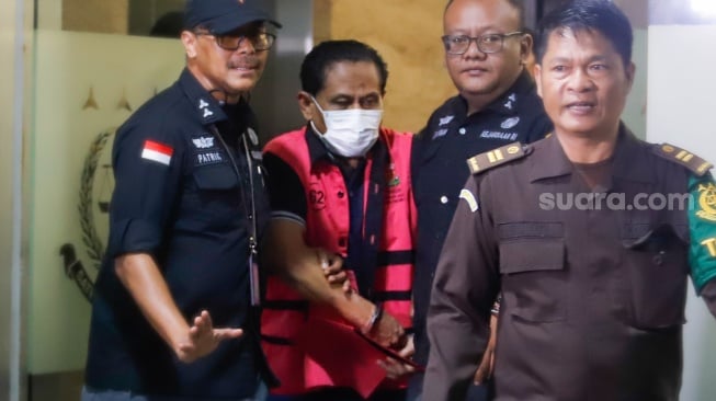 Petugas menggiring tersangka kasus dugaan suap hakim pembebas Gregorius Ronald Tannur Rudi Suparmono (tengah) keluar dari Gedung Kejaksaan Agung, Jakarta, Selasa (14/1/2025). [Suara.com/Alfian Winanto]