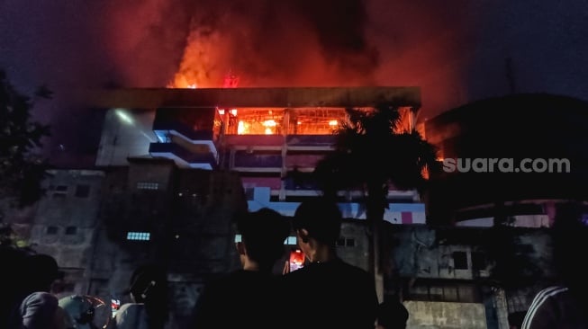 Warga melihat Gedung Glodok Plaza yang terbakar di Jakarta, Kamis (16/1/2025) dini hari. [Suara.com/Alfian Winanto]