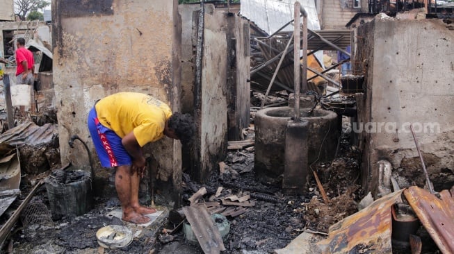 Warga mengambil barang sisa kebakaran di pemukiman padat penduduk, kawasan Kemayoran, Jakarta, Selasa (21/1/2025). [Suara.com/Alfian Winanto]