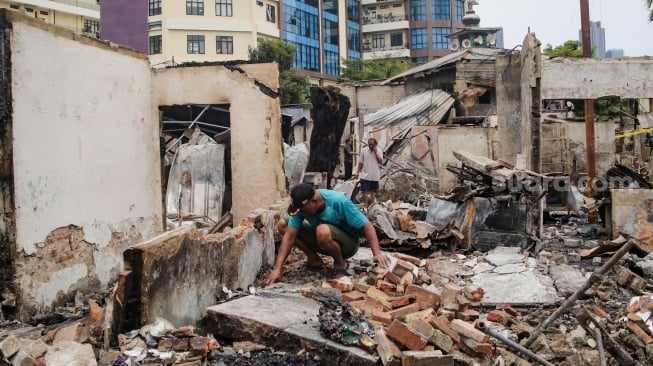 Warga mengambil barang sisa kebakaran di pemukiman padat penduduk, kawasan Kemayoran, Jakarta, Selasa (21/1/2025). [Suara.com/Alfian Winanto]