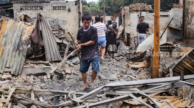 Warga mengambil barang sisa kebakaran di pemukiman padat penduduk, kawasan Kemayoran, Jakarta, Selasa (21/1/2025). [Suara.com/Alfian Winanto]