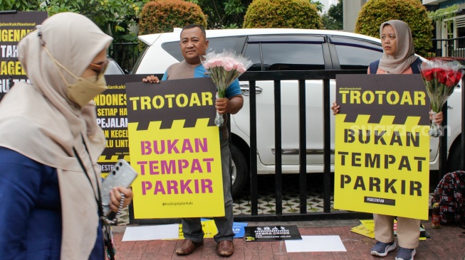 Aktivis dari Koalisi Pejalan Kaki menggelar aksi di Halte Tugu Tani, Jakarta, Rabu (22/1/2025). [Suara.com/Alfian Winanto