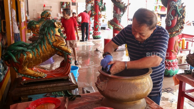 Warga keturunan Tionghoa membersihkan area ibadah di Vihara Amurva Bhumi, Jakarta, Rabu (22/1/2025). [Suara.com/Alfian Winanto]