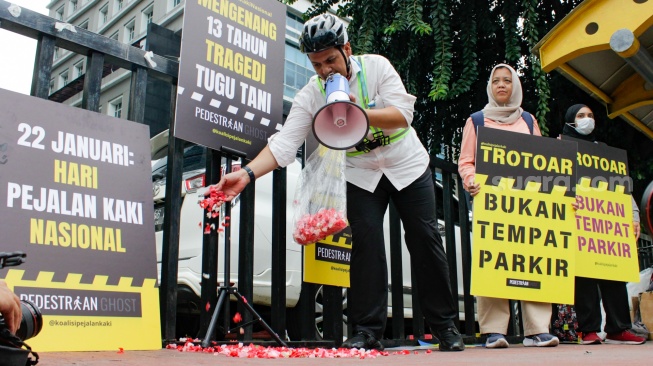 Aktivis dari Koalisi Pejalan Kaki menggelar aksi tabur bunga di Halte Tugu Tani, Jakarta, Rabu (22/1/2025). [Suara.com/Alfian Winanto