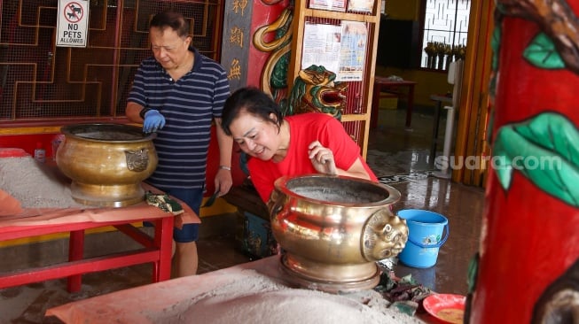 Warga keturunan Tionghoa membersihkan area ibadah di Vihara Amurva Bhumi, Jakarta, Rabu (22/1/2025). [Suara.com/Alfian Winanto]