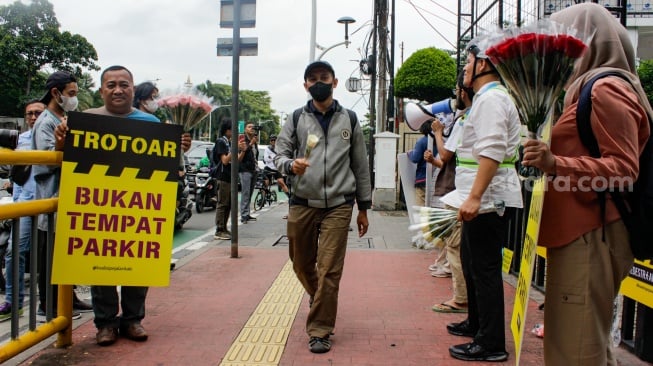 Aktivis dari Koalisi Pejalan Kaki menggelar aksi di Halte Tugu Tani, Jakarta, Rabu (22/1/2025). [Suara.com/Alfian Winanto