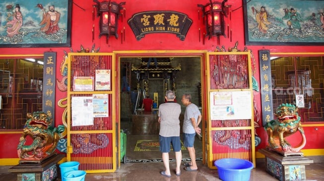 Warga keturunan Tionghoa membersihkan area ibadah di Vihara Amurva Bhumi, Jakarta, Rabu (22/1/2025). [Suara.com/Alfian Winanto]