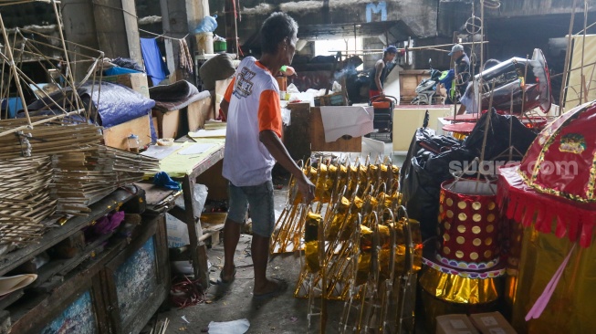 Perajin membuat replika barang-barang untuk sembahyang yang terbuat dari kertas di Kolong Tol Gedong Panjang, Jakarta, Kamis (23/1/2025). [Suara.com/Alfian Winanto]