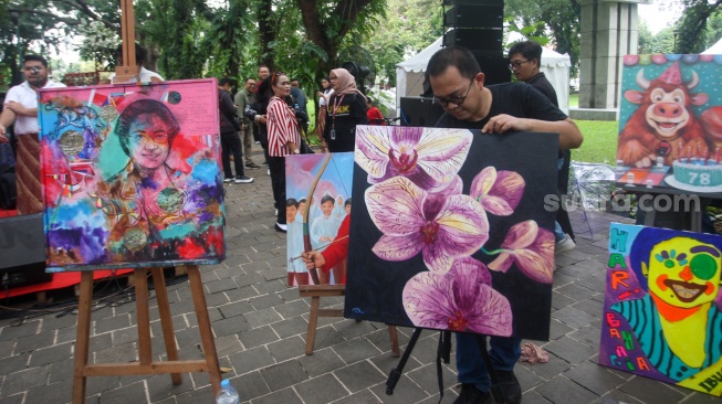 Seniman melukis wajah Megawati Soekarnoputri di Taman Suropati, Jakarta, Kamis (23/1/2025). [Suara.com/Alfian Winanto]