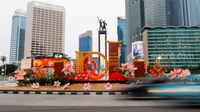 Sejumlah pengendara sepeda motor melintasi dekorasi Tahun Baru Imlek di Bundaran HI, Jakarta, Senin (27/1/2025). [Suara.com/Alfian Winanto]