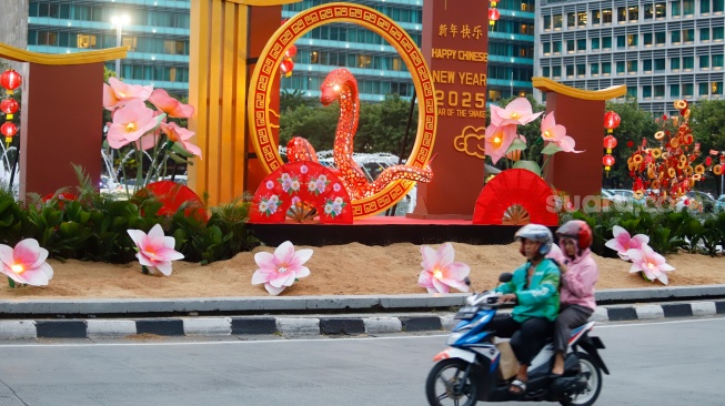 Sejumlah pengendara sepeda motor melintasi dekorasi Tahun Baru Imlek di Bundaran HI, Jakarta, Senin (27/1/2025). [Suara.com/Alfian Winanto]