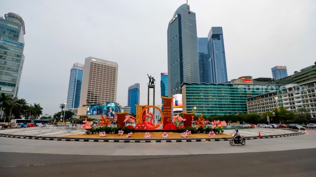 Sejumlah pengendara sepeda motor melintasi dekorasi Tahun Baru Imlek di Bundaran HI, Jakarta, Senin (27/1/2025). [Suara.com/Alfian Winanto]