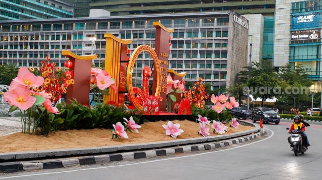 Sejumlah pengendara sepeda motor melintasi dekorasi Tahun Baru Imlek di Bundaran HI, Jakarta, Senin (27/1/2025). [Suara.com/Alfian Winanto]