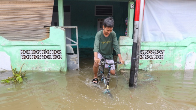 Warga beraktivitas di tengah banjir yang terjadi di pemukiman, kawasan Cakung, Jakarta, Rabu (29/1/2025). [Suara.com/Alfian Winanto]