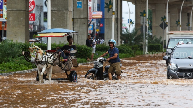 Pengendara melintasi banjir di Jalan Boulevard Raya, Kelapa Gading, Jakarta, Rabu (29/1/2025). [Suara.com/Alfian Winanto]