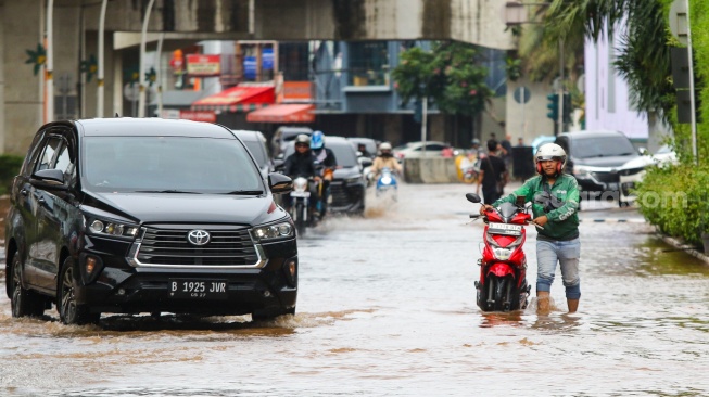 Pengendara melintasi banjir di Jalan Boulevard Raya, Kelapa Gading, Jakarta, Rabu (29/1/2025). [Suara.com/Alfian Winanto]